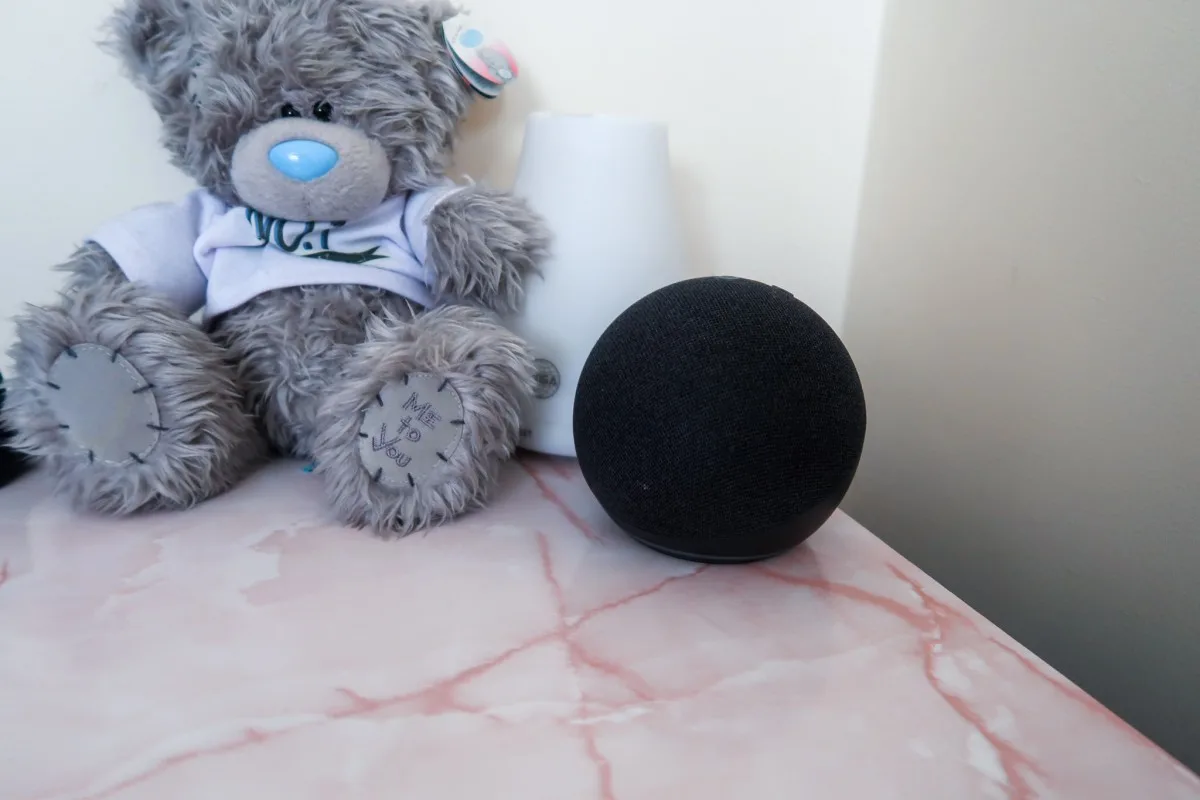 A bedside tablet with pink marble effect top, a me to you teddy that says 'no 1 father' and an Amazon Echo dot 4th generation device
