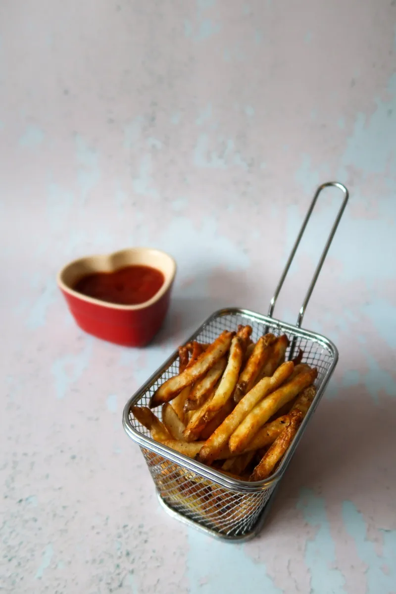 Air fryer fries in a basket with ketchup
