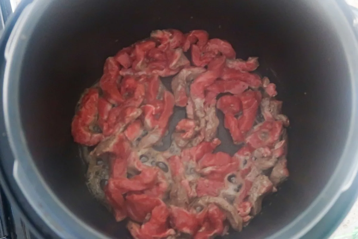 Beef browning in slow cooker pot for slow cooker beef stroganoff