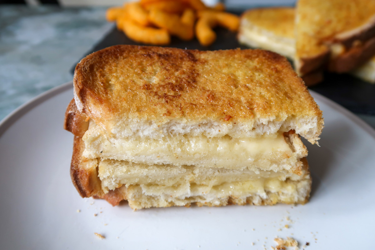 A cooked air fryer grilled cheese sandwich cut in half on a plate