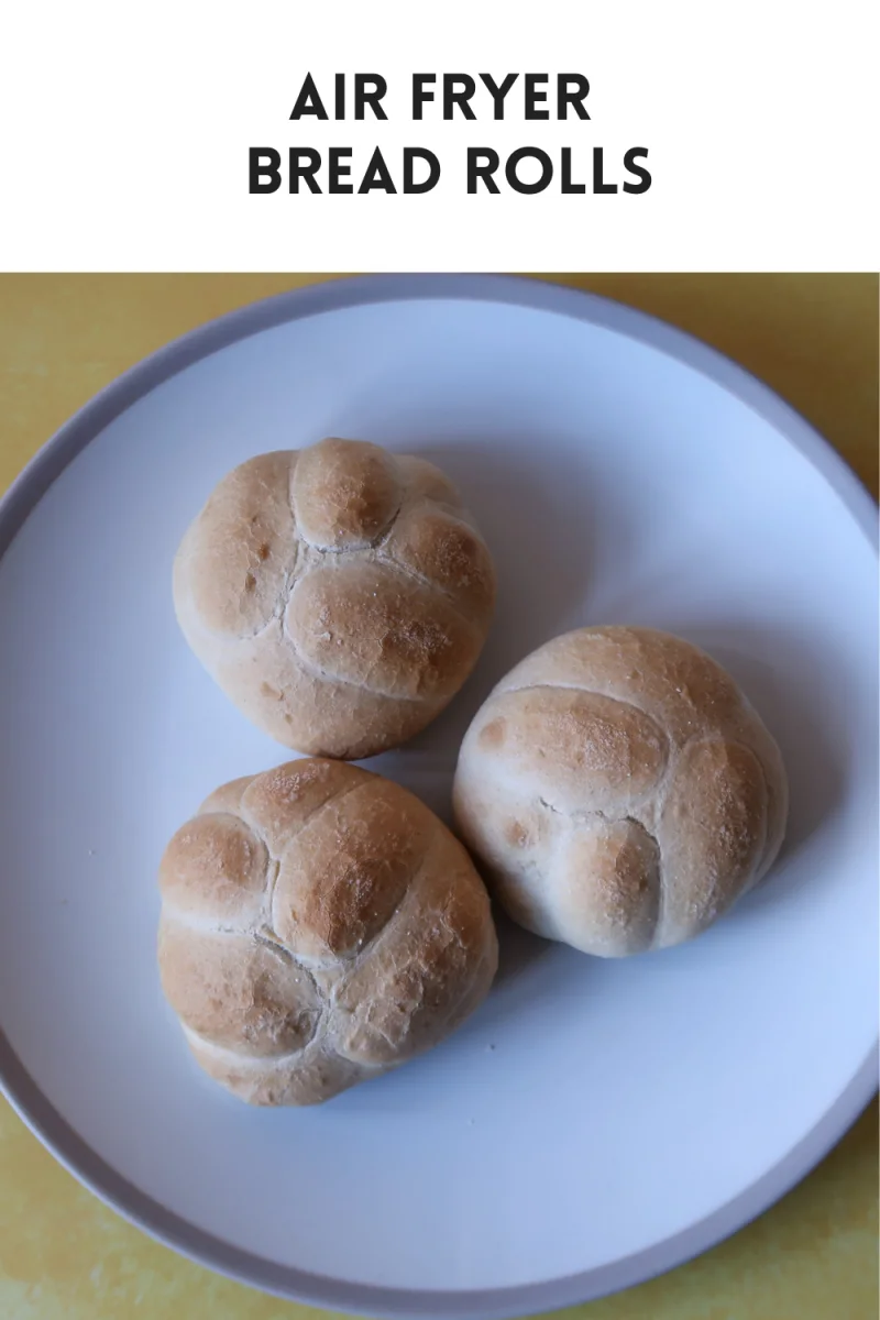 Bread rolls baked in the air fryer - three rolls on a plate with a pattern on the top of each one that resembles petals on a flower. Text overlay that says air fryer bread rolls