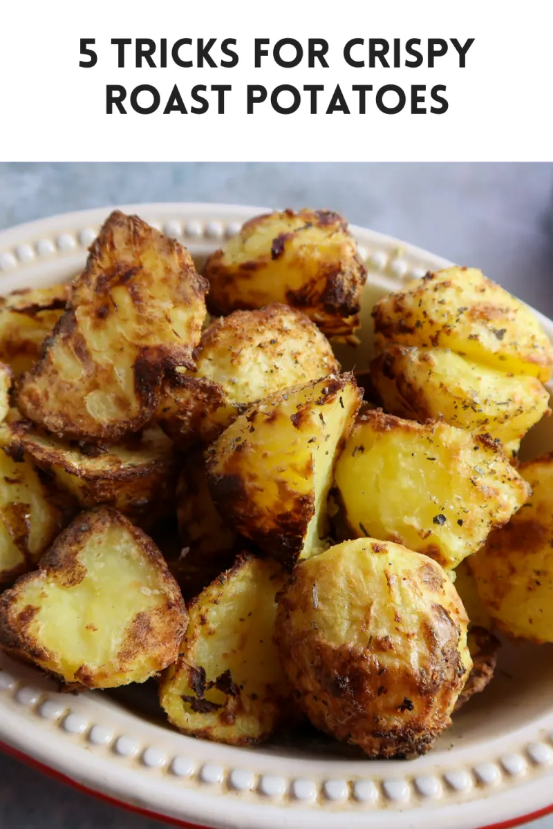 Ninja foodi roast potatoes in a red Le Creuset dish with 5 tricks for crispy roast potatoes written in text