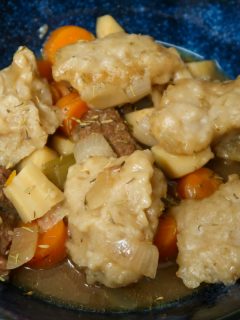 Cooked slow cooker beef casserole with dumplings in a blue dish